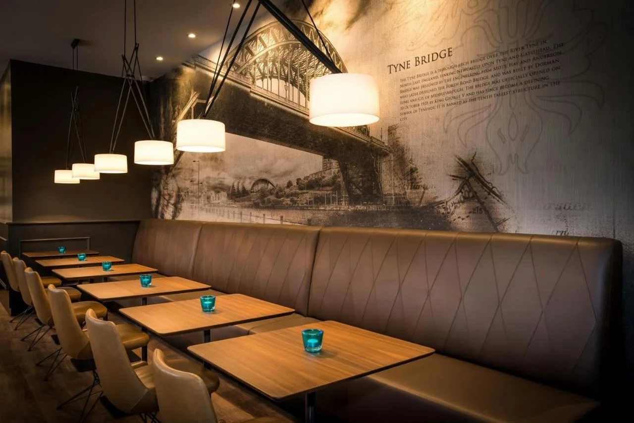 a row of tables in a restaurant with lights at Motel One Newcastle in Newcastle upon Tyne