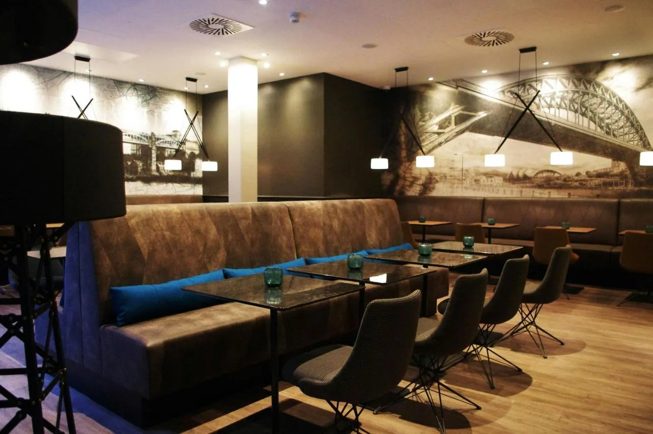 a restaurant with a couch and tables and chairs at Motel One Newcastle in Newcastle upon Tyne